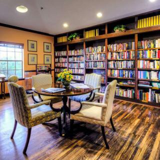 A cozy library with bookshelves filled with books, featuring a round table and chairs.