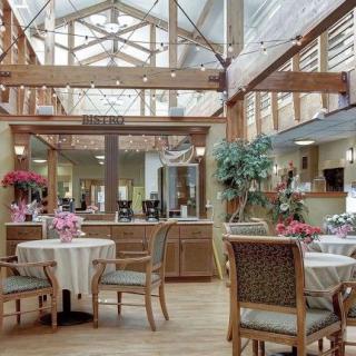 A bright and airy dining area with tables and chairs, decorated with plants and illuminated by a large skylight.