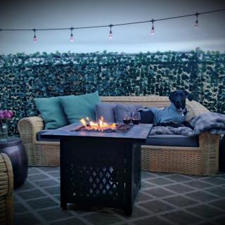 Cozy outdoor patio with a fire pit, wicker seating, and string lights, perfect for relaxing evenings.