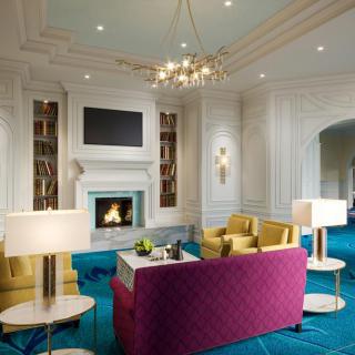 A luxurious living room featuring a vibrant color scheme with a central fireplace and elegant chandelier.