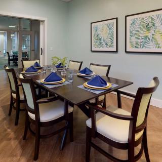 A neatly arranged dining room with a dark wooden table, complemented by upholstered chairs and vibrant blue napkins.
