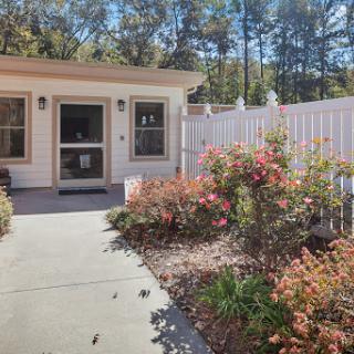 A charming entrance to a house surrounded by colorful flowers and a white fence.