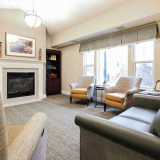 A cozy living room with a fireplace, seating area, and large windows.