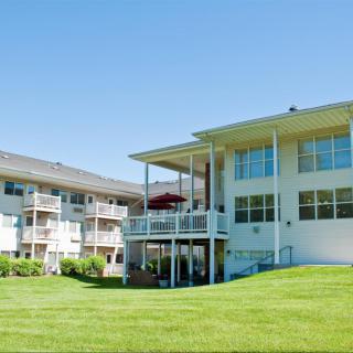 A residential apartment complex with well-maintained lawns and balconies on a sunny day.