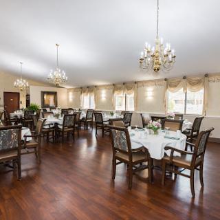 A spacious and elegantly decorated dining room featuring wooden furniture and chandeliers.