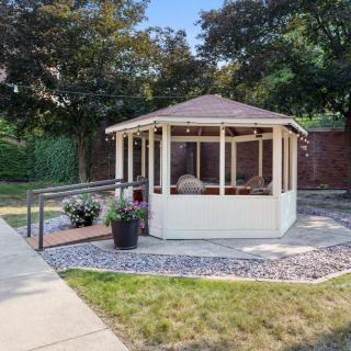 A charming gazebo surrounded by a manicured garden with a stone pathway leading up to it.