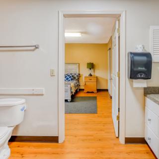 A view from a bathroom into a healthcare facility room with a bed.