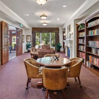 A cozy library with bookshelves, comfortable seating, and a table for reading.