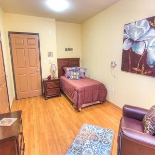A cozy bedroom with a single bed, nightstand, and artwork on the wall.