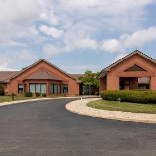 A view of a modern brick building complex with a landscaped entrance on a cloudy day.