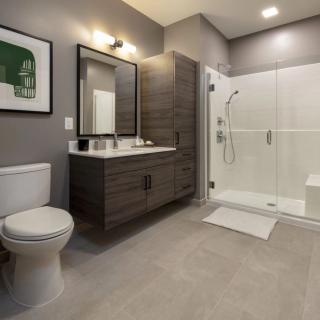 A modern bathroom featuring a glass-enclosed shower, a sleek vanity with a mirror, and contemporary lighting.