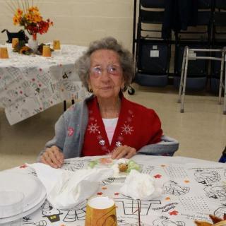 An elderly person sitting at a decorated dining table.