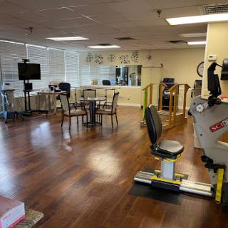 A spacious and well-equipped rehabilitation gym featuring exercise machines and a comfortable seating area.