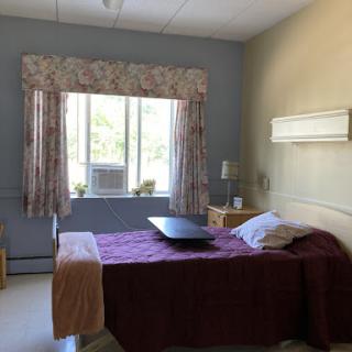 A serene hospital room featuring a bed, window with curtains, and minimalistic decor.