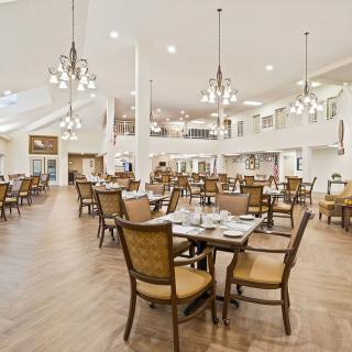 An elegant dining room interior with neatly arranged tables and chairs under stylish chandeliers.