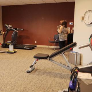 A small fitness center equipped with a treadmill, exercise bike, and bench for workouts.