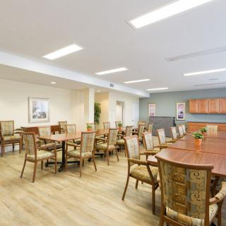 A spacious and well-lit dining area with multiple tables and chairs arranged for communal gatherings.