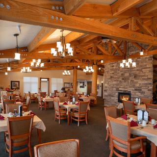 A cozy restaurant dining area with wooden beams, chandeliers, and a fireplace.