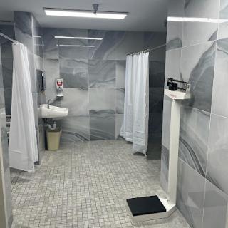 A modern bathroom featuring separate shower stalls with white curtains and a minimalist aesthetic.