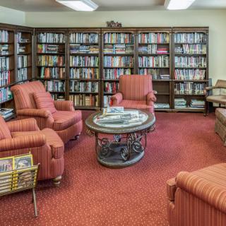 A cozy library reading room with comfortable chairs and shelves filled with books.