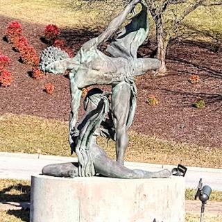 A striking bronze sculpture representing human figures in dynamic poses, set against a backdrop of autumn foliage.