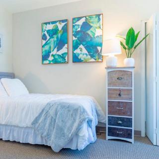 A cozy bedroom with a single bed, vibrant artwork, and a stylish lamp illuminating the room.
