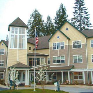 A multi-story residential building with a flagpole and surrounding trees.