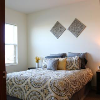 A cozy bedroom with patterned bedding, decorative pillows, and wall art.