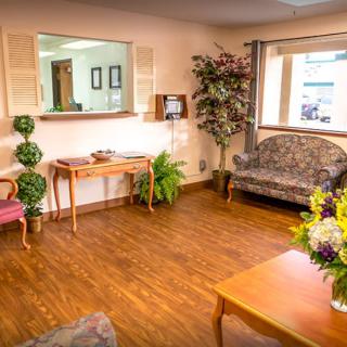 A cozy waiting area with comfortable seating, floral decorations, and a warm wooden floor.