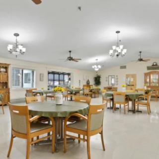 A spacious and well-lit dining area with multiple tables and chairs, featuring ceiling fans and chandeliers.