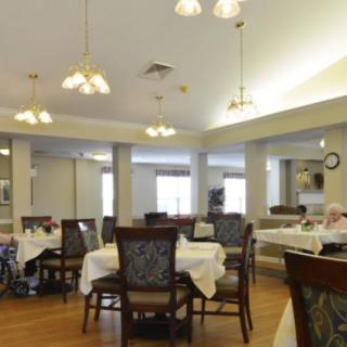 An indoor dining area with multiple tables and chairs, featuring overhead lighting.