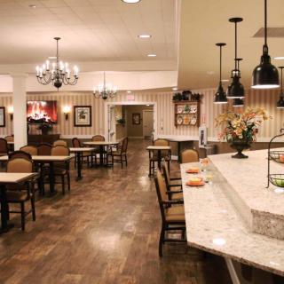 Cozy restaurant interior with a mix of dining tables, chairs, and a counter under warm lighting.
