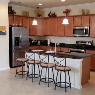 Modern kitchen with wooden cabinets, island counter, and bar stools.