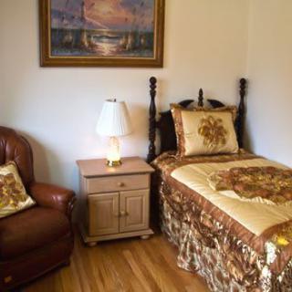A cozy bedroom with a single bed, armchair, and a side table with a lamp.