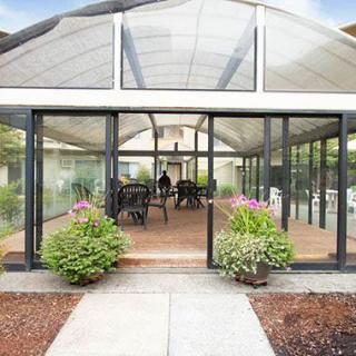 A glass-enclosed greenhouse with outdoor seating and potted plants.