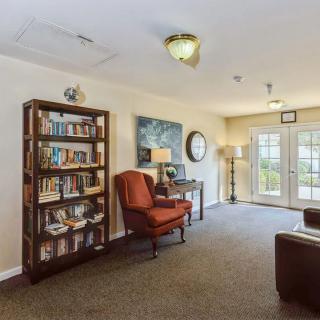 A cozy living room with a bookshelf, armchair, and decorative artwork.