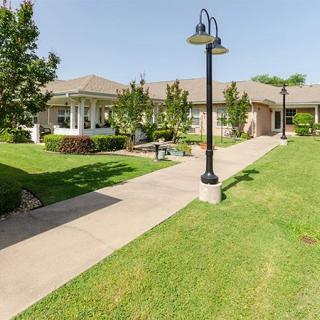 A well-maintained building with a surrounding lawn and trees, featuring a sidewalk and lamp posts.