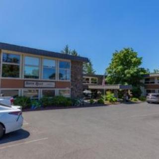 A two-story building with a parking lot and trees on a sunny day.