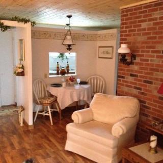 A cozy living room with an adjoining dining area featuring a brick wall and wooden flooring.