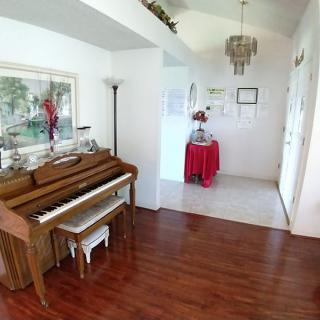 A cozy living room featuring a wooden piano, hardwood floors, and elegant decor.