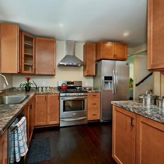A modern kitchen with wooden cabinets, granite countertops, and stainless steel appliances.