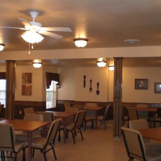 A spacious dining area featuring tables, chairs, and a ceiling fan, designed for comfort.