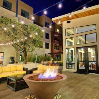 A cozy outdoor patio area with a fire pit, surrounded by comfortable seating and illuminated by string lights.