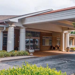 The image shows the front entrance of a modern building with columns and a covered walkway.