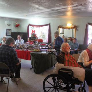 A group of seniors socializing in a decorated indoor space during a holiday gathering.