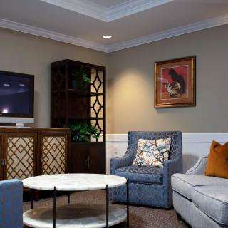 A cozy living room featuring a comfortable sofa, stylish armchair, and a modern coffee table. The room is accented with artwork on the wall and a television for entertainment.