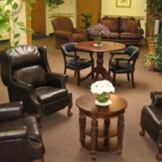 Comfortable lounge area with leather chairs and a wooden table surrounded by plants.