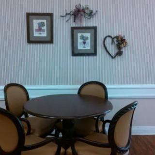 A cozy dining area with a round table and four chairs, adorned with framed art and floral wall decor.