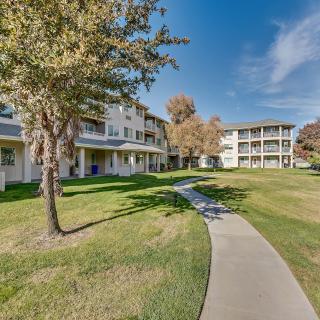 A scenic view of an apartment complex with a winding pathway surrounded by green grass and trees.