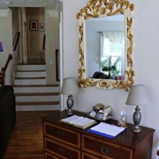 A cozy hallway featuring a decorative mirror, wooden desk, and lamps.